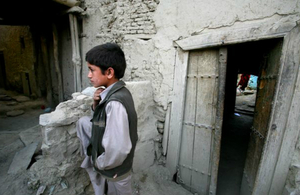 This picture shows a young Afghan boy standing in a yard