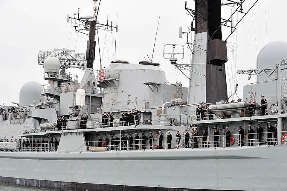 HMS Gloucester's ship's company line the decks as they leave Portsmouth for seven months