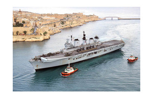 Tugs help to guide HMS Illustrious into the port of Valletta