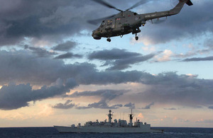 HMS Cumberland with the ship's Lynx helicopter flying overhead
