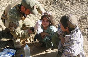 Lance Corporal Craig Murfitt gives first aid to an Afghan girl
