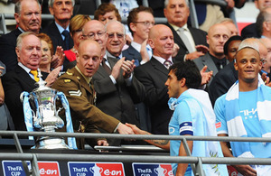 Corporal Mark Ward shakes hands with Carlos Tevez, the captain of Manchester City, prior to presenting the trophy to the 2011 FA Cup winners