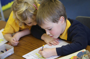 Two primary school children working at their desks.