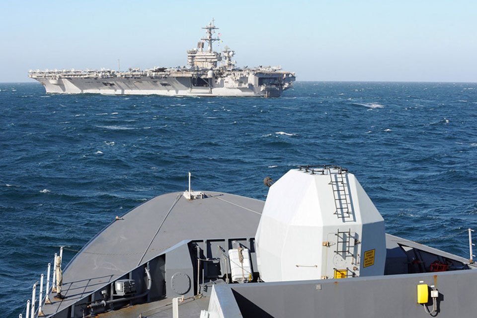 The bow of HMS Daring with United States Navy Nimitz Class aircraft carrier the USS Carl Vinson in the background