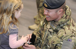 Corporal Jonathan Wilcox of 31 Squadron RAF, aged 32 from Kings Lynn, shows his daughter his Operational Service Medal