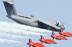 An A400M Air Transporter is accompanied by the Red Arrows