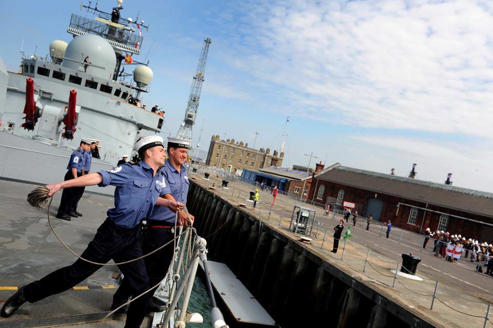 A sailor throws a heaving line from HMS Edinburgh