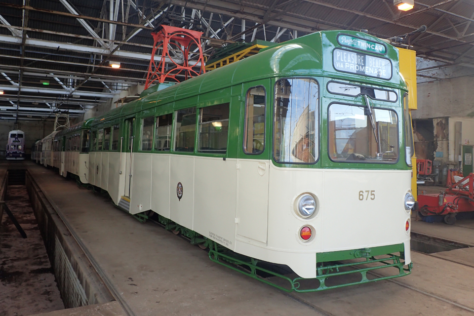 A Progress Twin-car tram in green and cream livery, similar to 272/T2. the tram is in the depot with other trams in the background. An open inspection pit is shown to the left hand side.