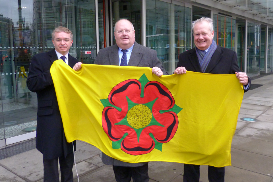 Eric Pickles holding the flag of Lancashire with two Lancashire MPs