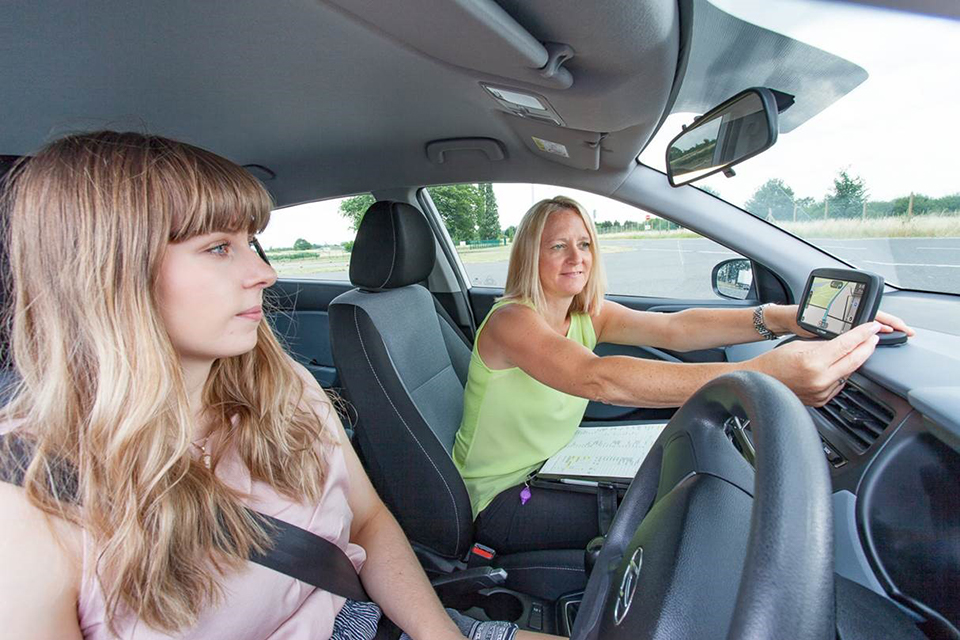 Driving test candidate with a driving examiner setting up a sat nav