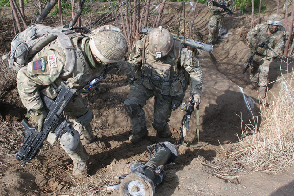 Soldiers from the 1st Battalion Irish Guards negotiate rough terrain during the operation in the town of Pasab 