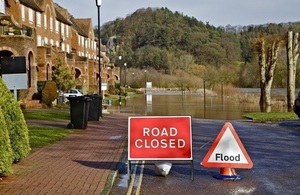 A road in front of a row of houses which is closed due to flood waters.