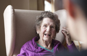 An elderly lady sitting on a chair smiling