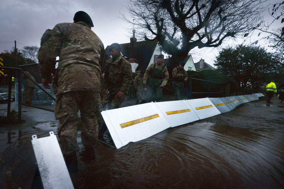 Soldiers erect flood defences alongside the River Thames