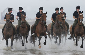 Horses from the King's Troop Royal Horse Artillery exercising on the beach in the shadow of the world-famous Blackpool Tower