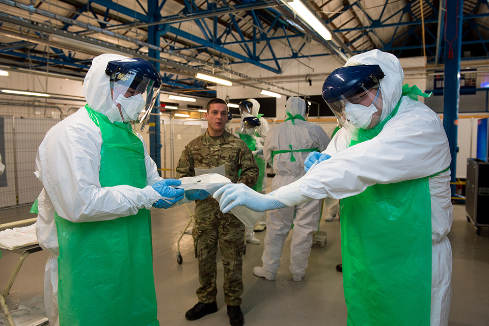A soldier training Army reservists on how to don personal protective equipment 