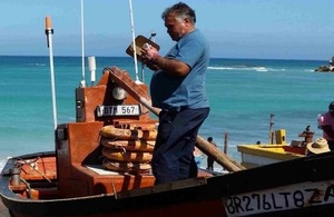 Image of man using mobile in small fishing boat.