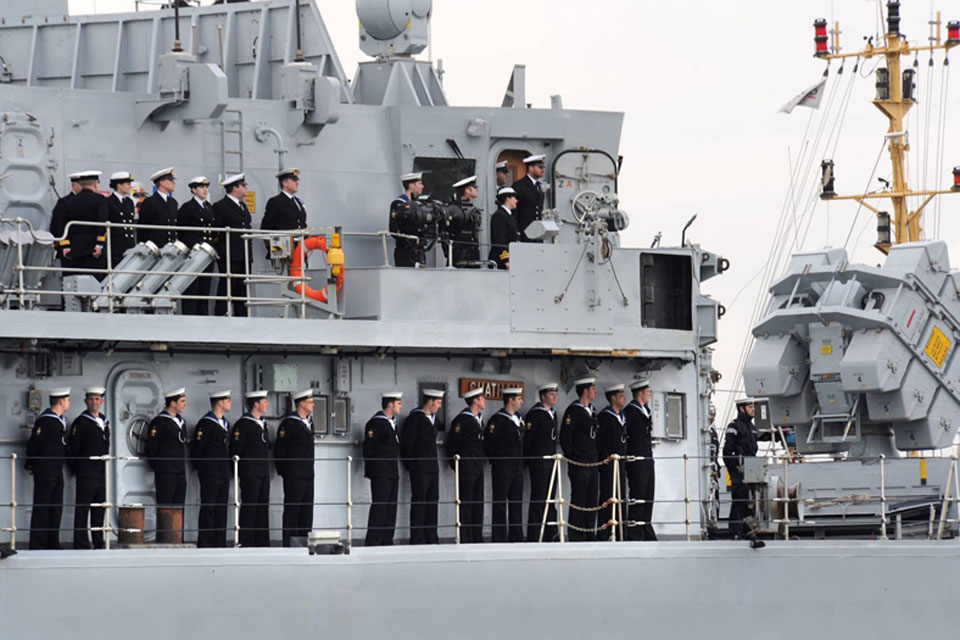 Members of HMS Chatham's crew lining her decks on the ship's final approach into Devonport Naval Base