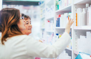 Pharmacist and customer search for medication on a shelf