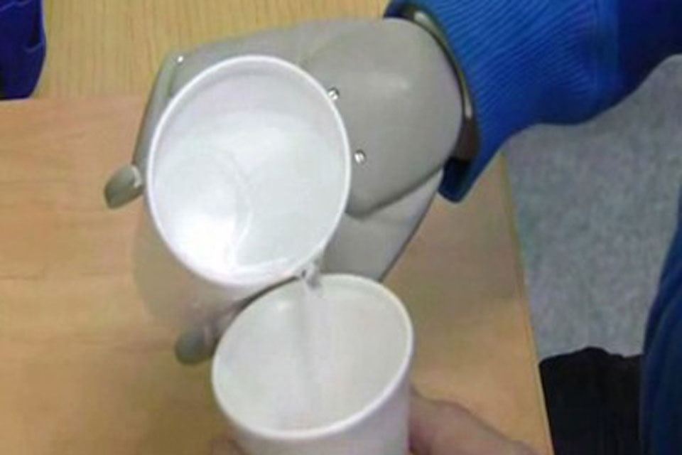 Corporal Garthwaite demonstrates his delicate control of the bionic arm by pouring water from one polystyrene cup into another