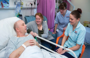 Photo of a relative and nurses around a hospital patient bedside