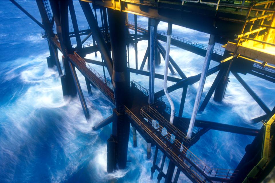 The sea crashing against the legs of an offshore oil platform