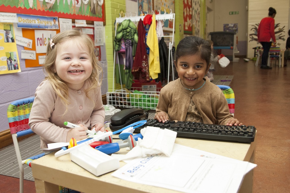 Two girls sitting at a table in a nursery.