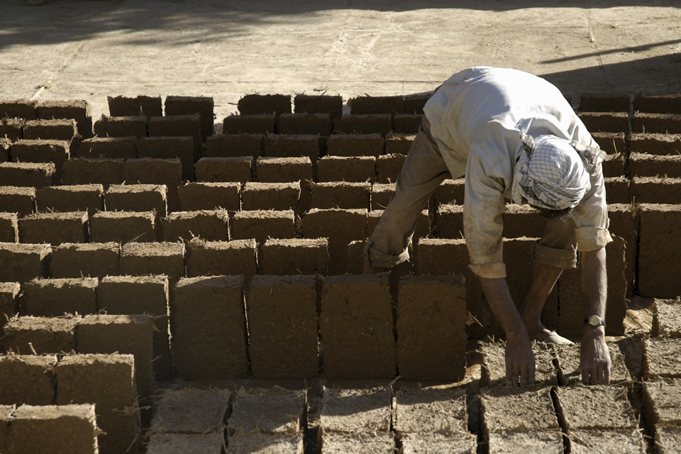 An Afghan worker uses traditional adobe blocks