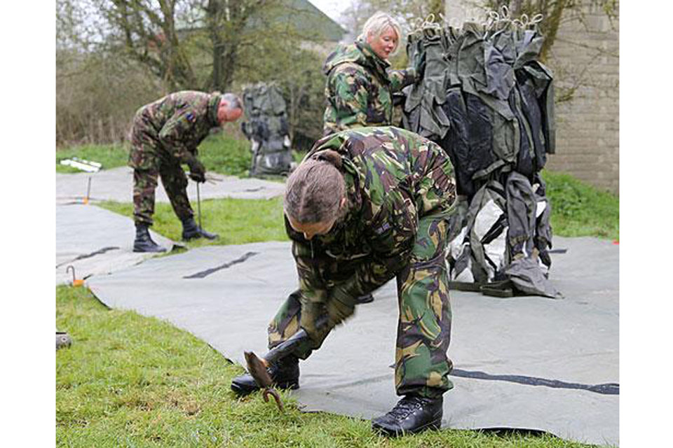 RAF reservists lay a groundsheet for a tented structure 