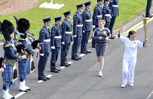 Sandie Kennedy carries the Olympic Torch past RAF Leuchars Main Gate