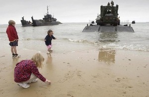 Children play on the beach at Arromanches in front of British landing craft (library image) [Picture: Giles Penfound, Crown copyright]