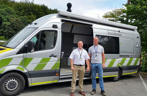 Two men standing outside large Incident Command Unit