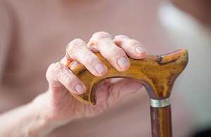 A woman with her hand on a walking stick.
