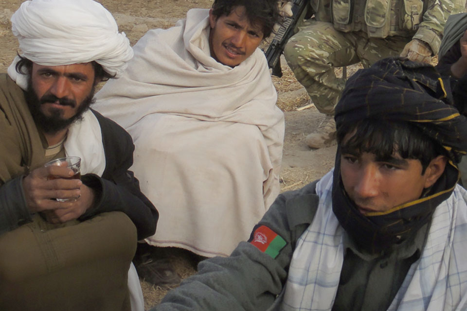 A member of the Afghan National Police with local residents at the shura in Noorzai 