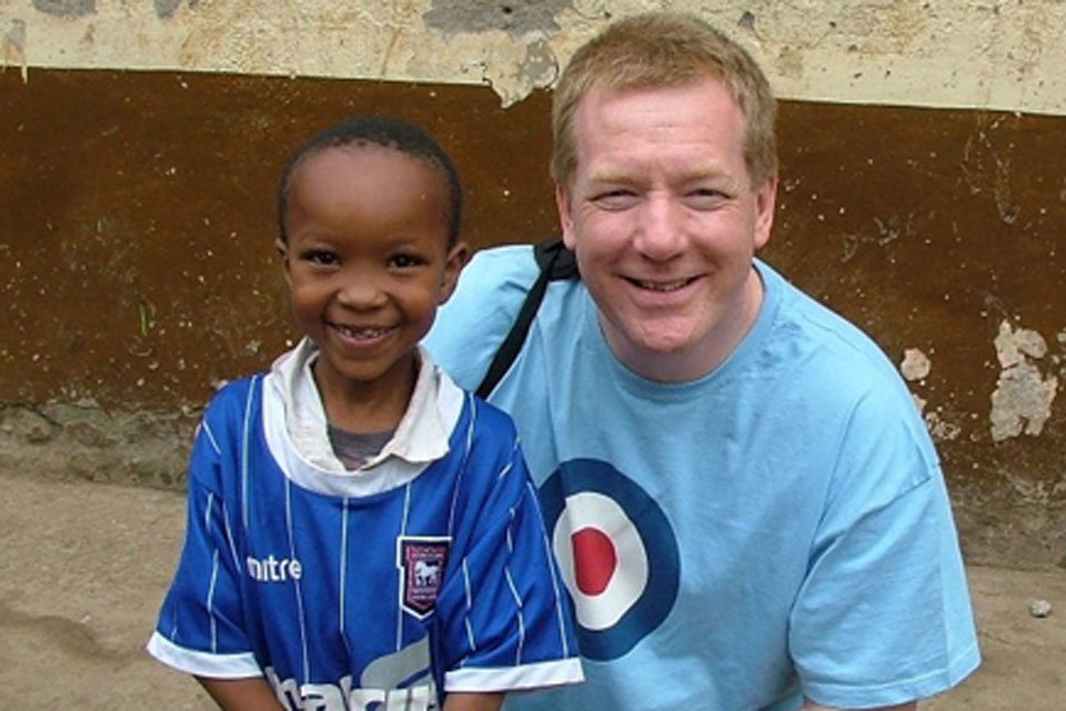 Squadron Leader Neil Hope with a small boy at the Mogra Star Academy in Kenya