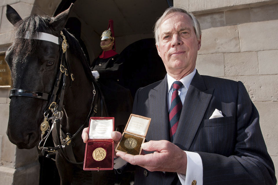 Lord Astor of Hever, Under-Secretary of State for Defence, displays his grandfather's Gold and Bronze medals from the London 1908 Olympics 