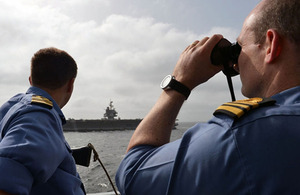 Members of HMS Diamond's ship's company observe flight deck operations being conducted on the USS Enterprise