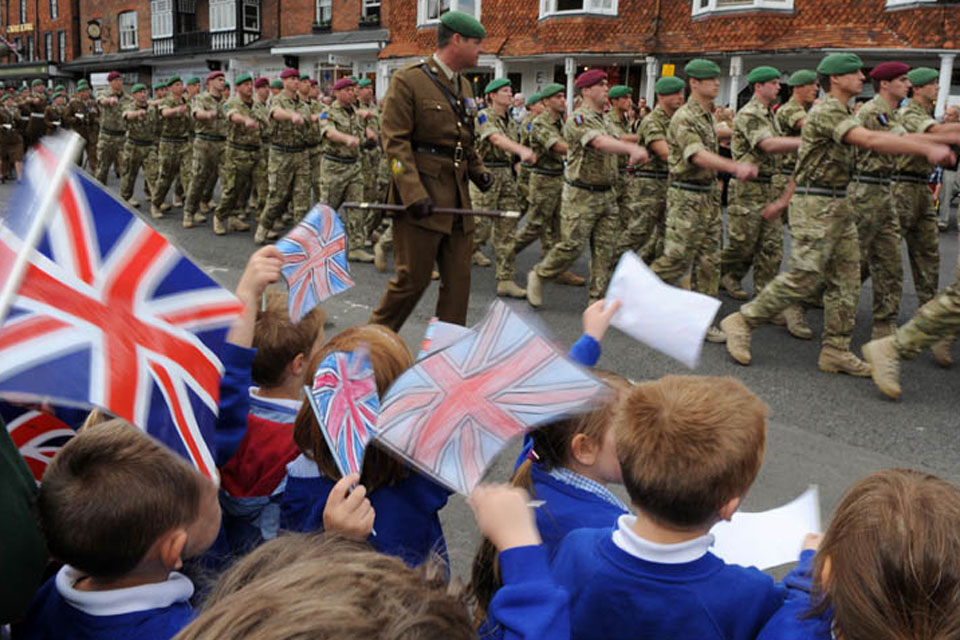 Schoolchildren cheer as soldiers from 4 Military Intelligence Battalion march through the historic Wiltshire town of Marlborough
