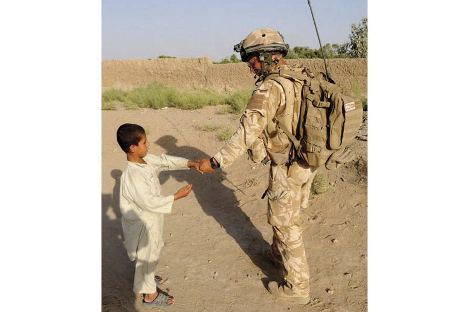 A RAF Regiment Gunner engages with an Afghan child while out on patrol 