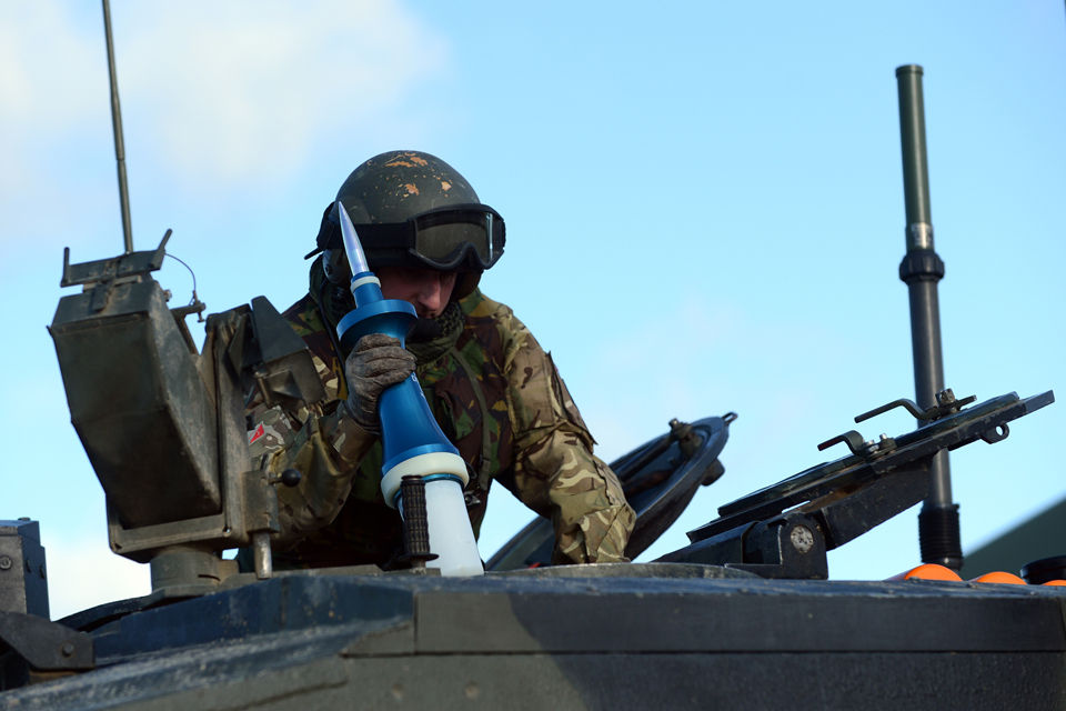 A reservist passes an armour-piercing round through the hatch of a Challenger 2