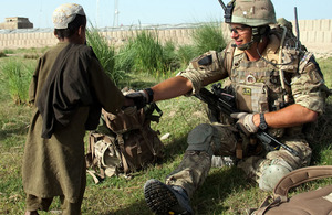Lieutenant Tom Lucy, K Company 42 Commando Royal Marines, greets an Afghan boy whilst on patrol with his section outside of Patrol Base 5 in Helmand Province, Afhanistan
