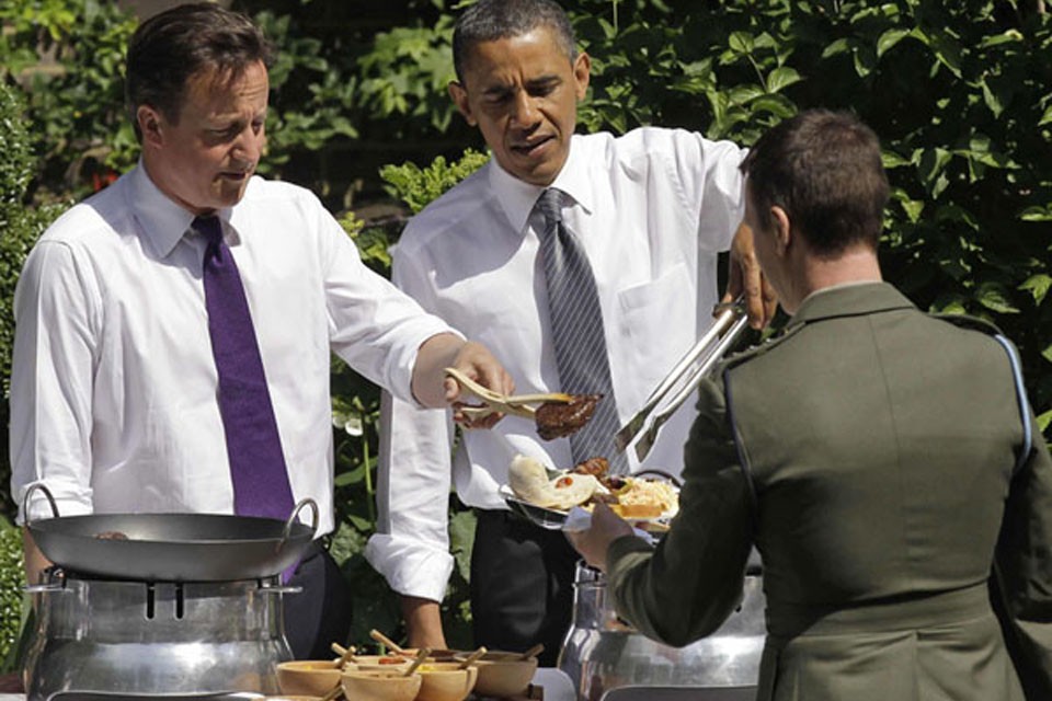 Prime Minister David Cameron and US President Barack Obama serve food to a serviceman during a barbecue in the garden of 10 Downing Street  