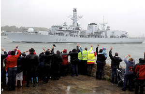 Friends and families wave to their loved ones as HMS Montrose passes Devil's Point