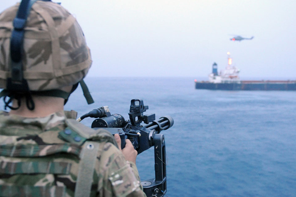 A member of HMS Monmouth's force protection team provides cover during the boarding of the merchant vessel