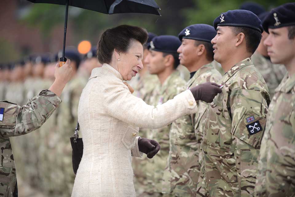 Princess Anne pins a medal to the chest of a soldier