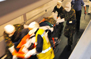 A mock casualty is transported at speed through RFA Argus by a stretcher team
