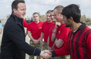 David Cameron shakes hands with British army personnel and a member of an Afghan football team.