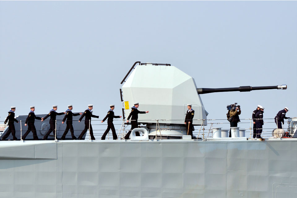 Members of the ship's company march past HMS Edinburgh's 4.5-inch gun