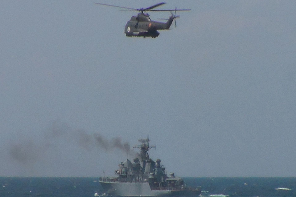 A Romanian helicopter flies over a Bulgarian minehunter as part of Exercise Poseidon