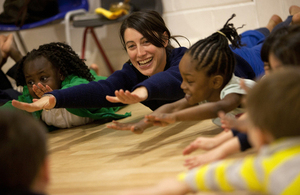 children and teaching assistant stretching on the floor